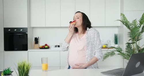Pregnant Woman Enjoys Pastry Snack in Kitchen