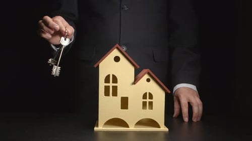Hand Holding Keys over Miniature House