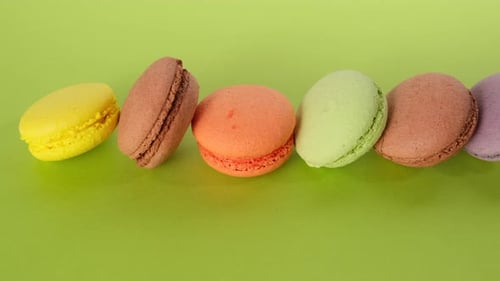 assortment of baked macarons on a green background, dessert lies in a row