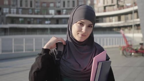 Schöne muslimische Frau im Hijab posiert an sonnigen Tagen mit Büchern im Freien. Porträt von Charming Middle