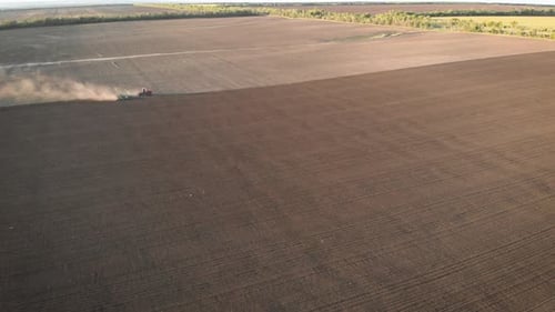Aerial View Modern Red Tractor on the Agricultural Field on Sunset Time. Tractor Plowing Land and