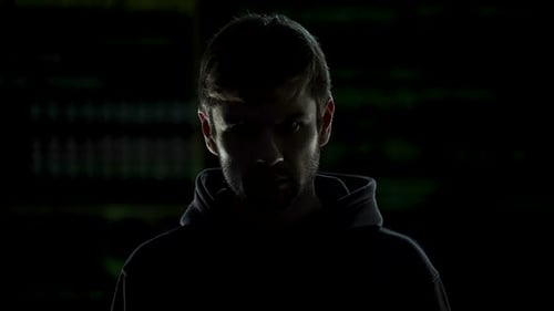 Jovem homem incógnito hacker da Internet colocando capuz negro, ameaça de cibercrime