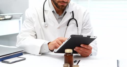 Doctor Using Tablet at Desk in Medical Office