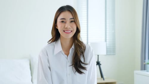 Smiling Woman Posing in White Bedroom Setting