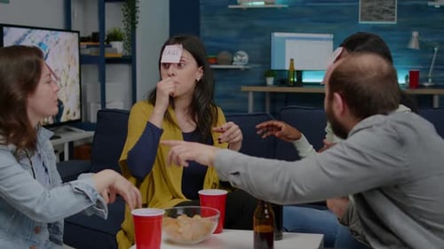 Mixed Race Friends Playing Guess Who Game with Sticky Papers Attached on Forehead