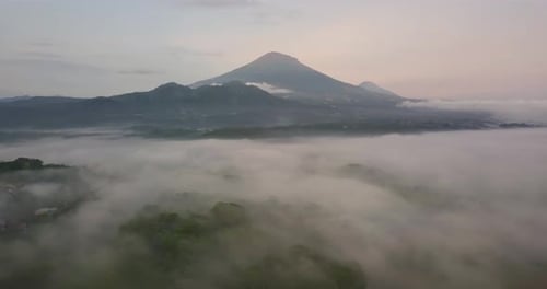 Drohnenflug über weiße Wolken zeigt den Gipfel des Mount Sumbing in Indonesien bei Sonnenuntergang