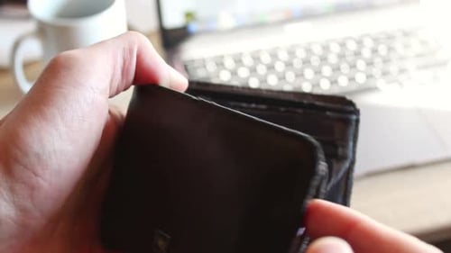 Hands opening a brown leather wallet with no money inside. Static close up shot in front of office b