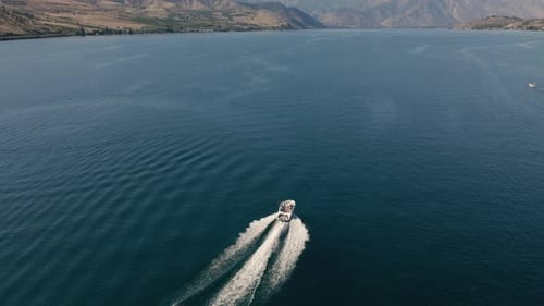 Pristine Blue Lake Water With Drone Following Motorboat Cruising In Desert Environment
