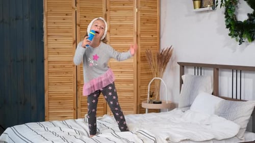 Energetic Girl Singing and Dancing on Bed