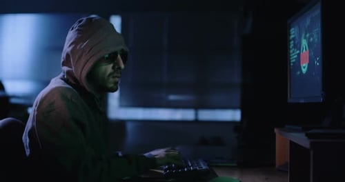 Pirate informatique assis dans une pièce noire piratant des systèmes de sécurité