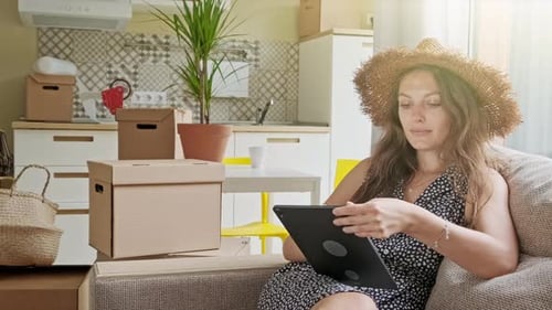 Woman on Couch With Tablet and Moving Boxes