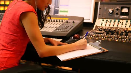 Woman Writes Notes at Sound Studio Desk