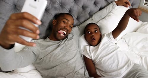 Man and Child Taking Selfie in Bed