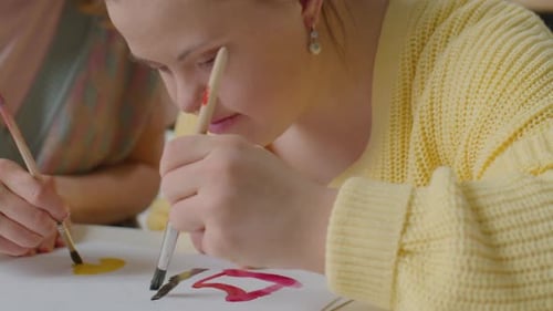 Woman and Teen Paint Together Indoors