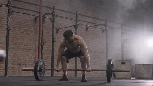 Muscular Sportsman Lifting Barbell during Intensive Training