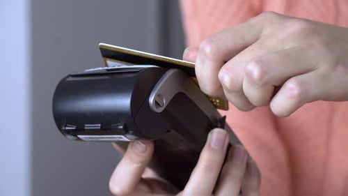a man's hand brings a plastic card to the terminal and pays contactless