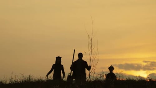 Young Family Having Fun Outdoors in Their Farm. Gardener Woman Pushing Wheelbarrow. Family Is Going