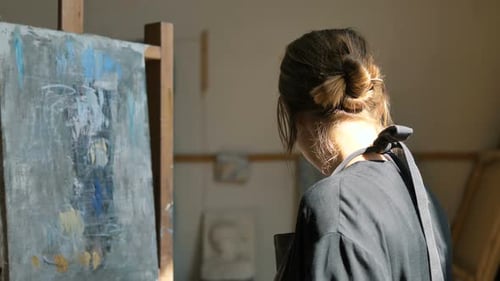Woman Artist Makes Blue Strokes of Paint on Canvas in Studio