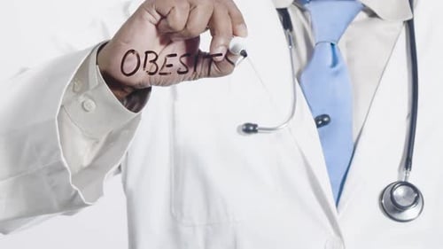 Doctor Writing "Obesity" on Transparent Surface