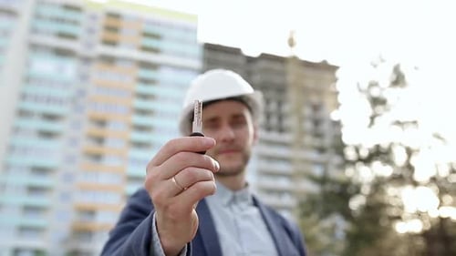 Der Baumeister zeigt den Schlüssel der Wohnung vor der Kamera