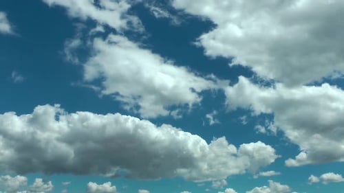 Fluffy White Clouds Float Across a Bright Blue Sky