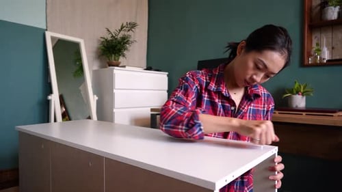 Woman Assembling Furniture at Home with Screwdriver