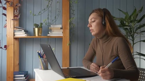 Woman works at laptop with headphones indoors