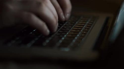 Young Guy Working At The Computer. Dark Room. Close-up.