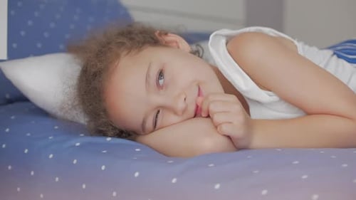 Young Girl Smiling While Resting in Bed