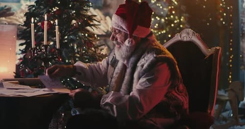 Santa Claus Reviewing Letters By Christmas Tree