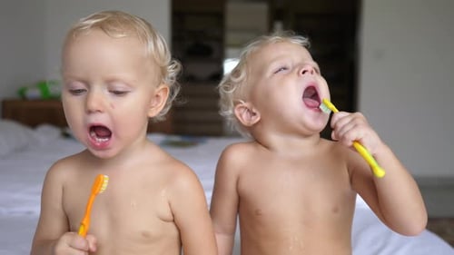 Two Children Brush Teeth Together in Bedroom