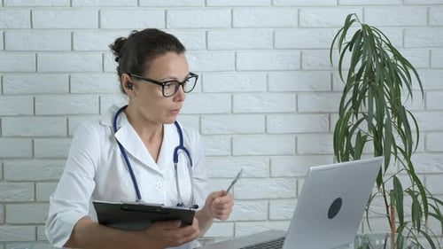 Female Doctor at Desk Using Laptop for Telehealth
