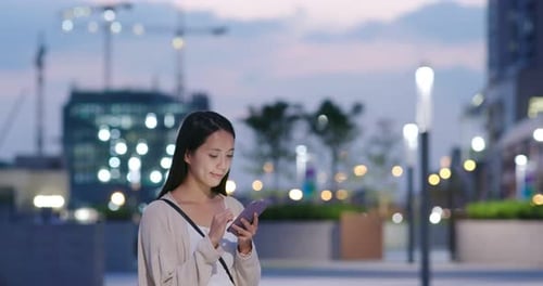 Utilisation d'un téléphone portable par une femme en ville la nuit