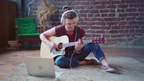 Man Plays Guitar with Laptop in Loft Apartment