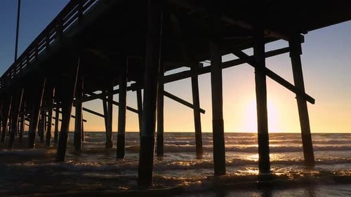 Aerial view under pier at Newport Beach as waves roll in