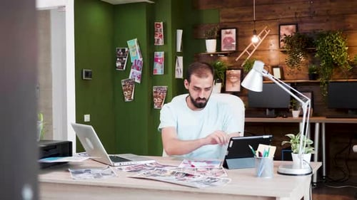Man Works at Desk on Laptop and Tablet