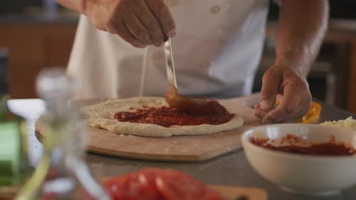 Chef Spreads Sauce on Pizza Dough at Home