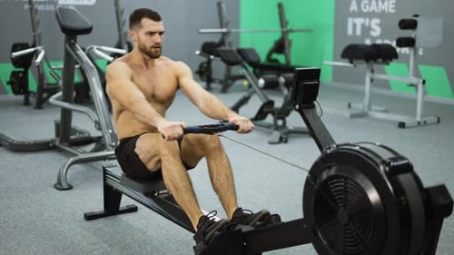 Muscular Man Working Out on Rowing Machine in Gym
