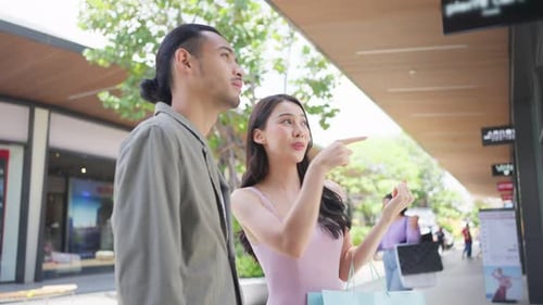 Asian young man and woman shopping goods outdoors in department store.