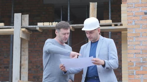 Vor dem Hintergrund des Baus von zwei Personen, die über das Projekt für den Bau diskutieren