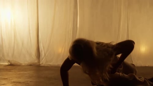 Silhouette of a Professional Dancer Performing in Studio in Soft Warm Lighting