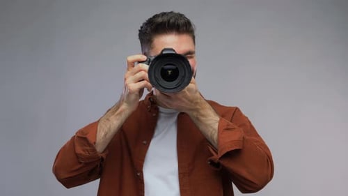Bearded Man Holding Camera and Smiling in Studio