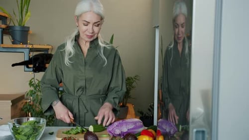Mature Woman Prepares Vegetables in Kitchen at Home
