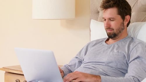 Man Relaxing in Bed, Using Laptop