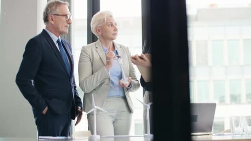 Team Discussing Green Energy Technology in Bright Office