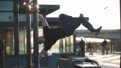 Sportive Man Training His Body on the Bars on Sports Ground
