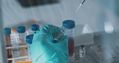 Gloved Hands Extracting Liquid from Vial in Lab