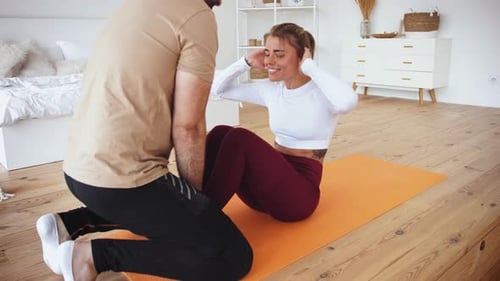 Young Couple is Doing Sport Excercises at Home in Cozy Bright Bedroom