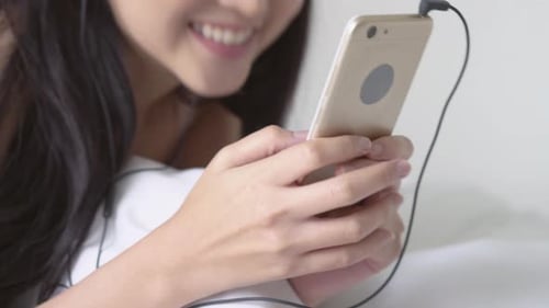 Young Woman Relaxes in Bed with Phone