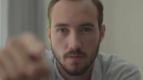 Portrait of Young Handsome Man Pointing in the Camera with His Finger Close-up, Focus Is on the Face